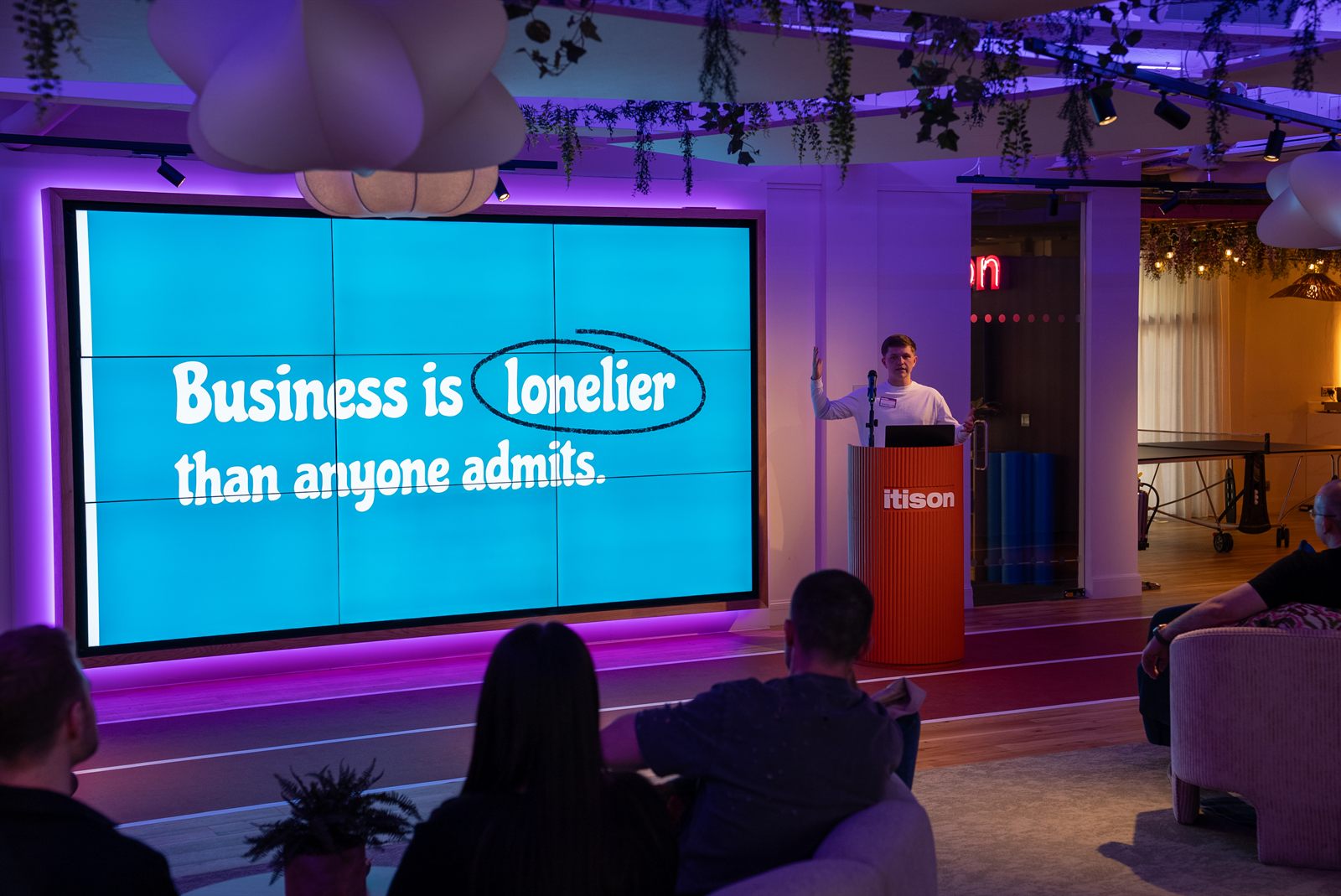 A founder on stage at a Focus on Founders event, with a screen reading Business is lonelier than anyone admits